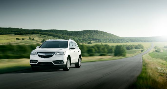 田舎の道を走る白いSUV車