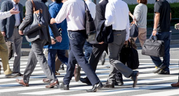 スーツを着たビジネスパーソンたちが横断歩道を渡っている