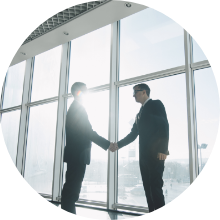 大きな窓の前で握手するビジネスパーソン二人